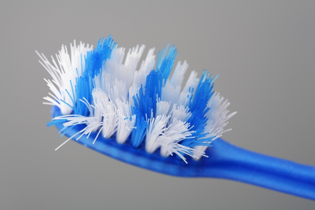 Worn toothbrush in closeup on grey background